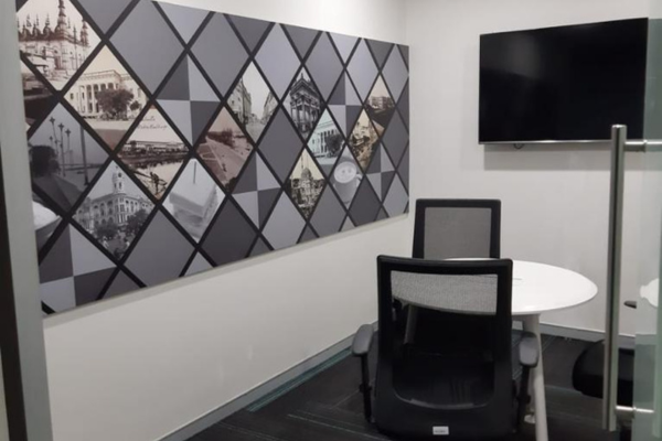 Modern private office or huddle room at Infinity Business Centre featuring a wall-mounted screen, small table, and comfortable chairs, ideal for focused work or small meetings.