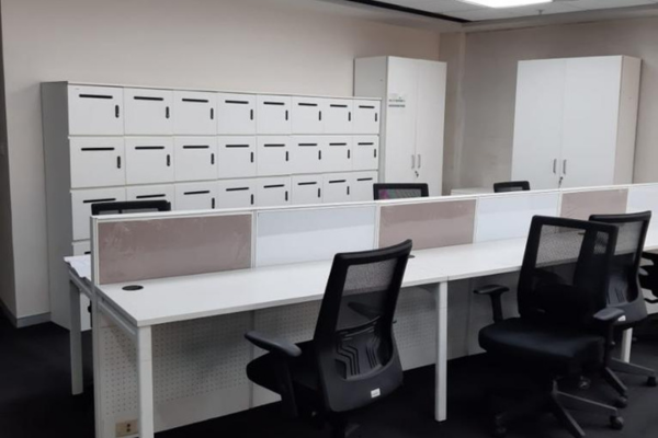 Modern coworking area at Infinity Business Centre, showing clean white desks with partitions and secure personal lockers, offering a flexible and convenient solution for professionals.